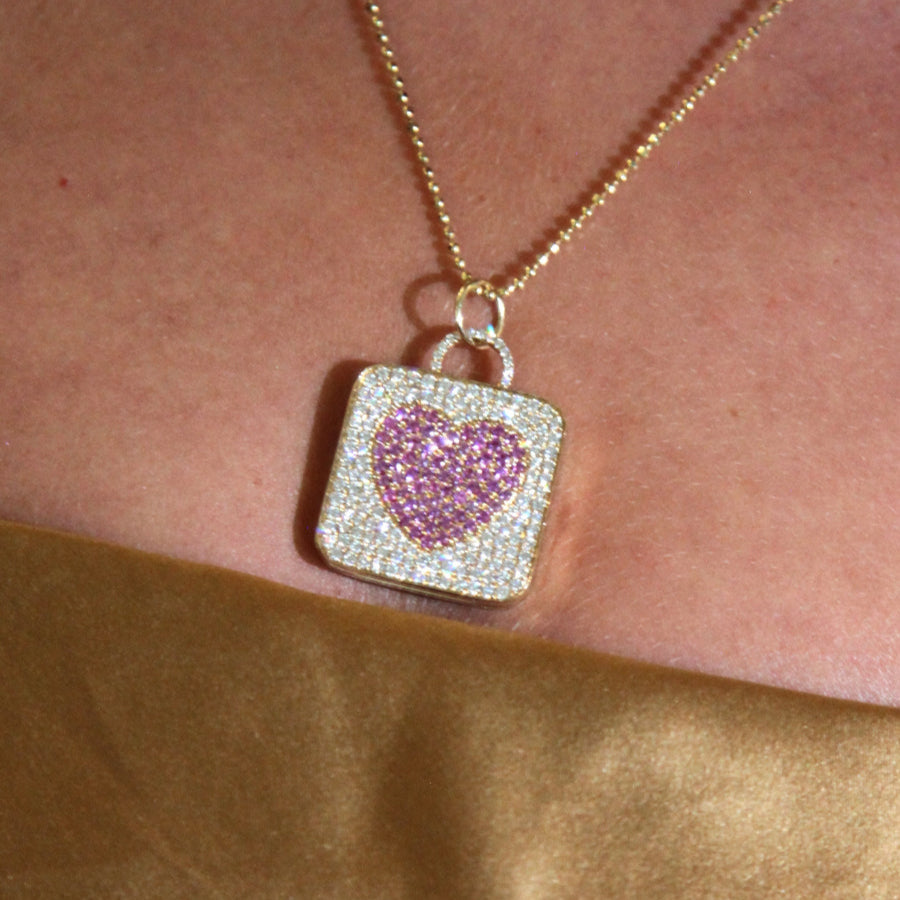 Gold locket necklace with a pink heart pendant.