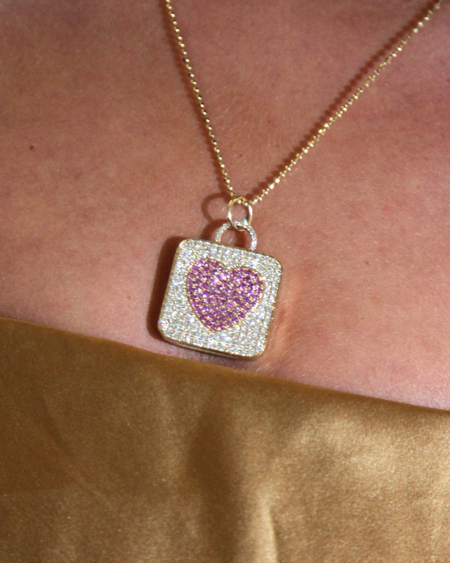 Gold locket necklace with a pink heart pendant.