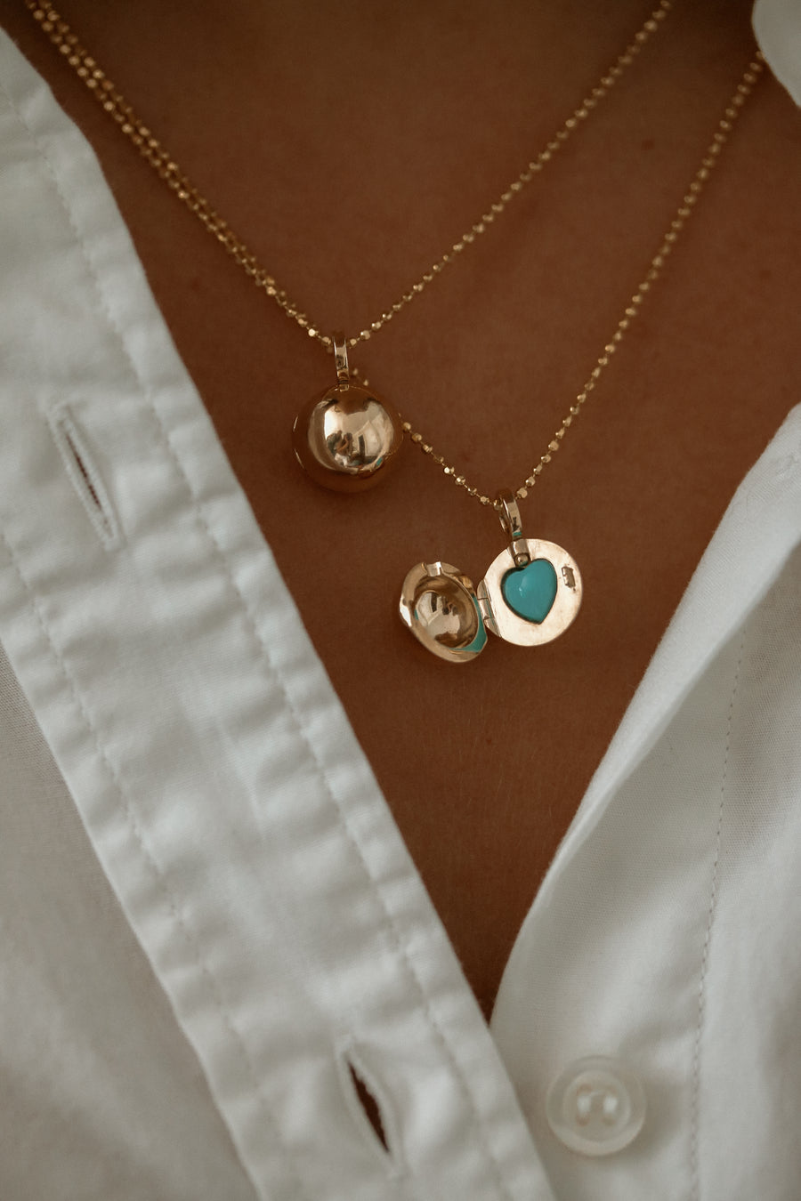 14k ball locket necklace adorned with a captivating turquoise heart center stone, exuding charm and elegance. This unique piece features a spherical locket design, complemented by the vibrant turquoise heart at its center. The rich blue-green hue of the turquoise stone adds a pop of color and sophistication to the understated beauty of the gold locket, making it a stunning addition to any jewelry collection.